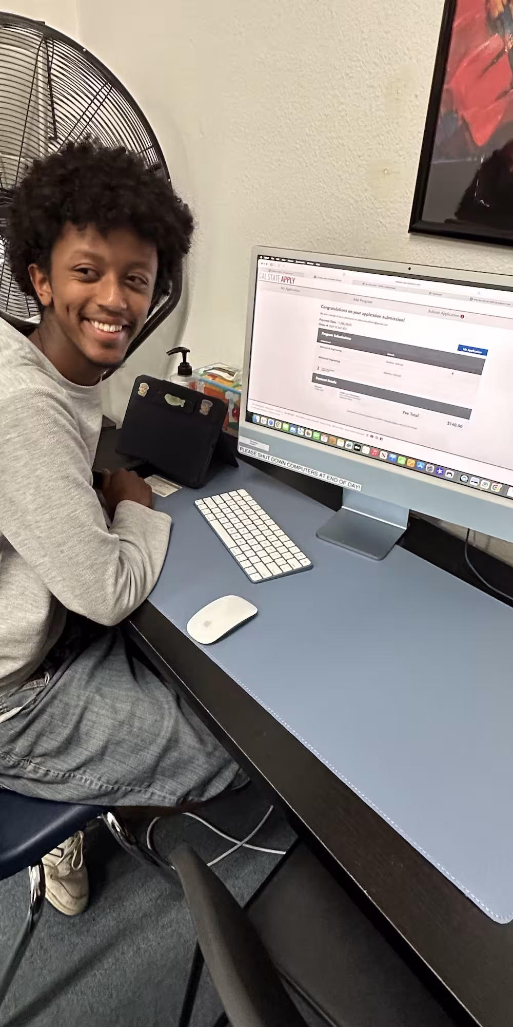 A student smiling while working at a computer during a college readiness session.