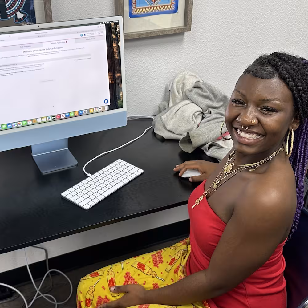 A student smiling while working at a desktop computer.