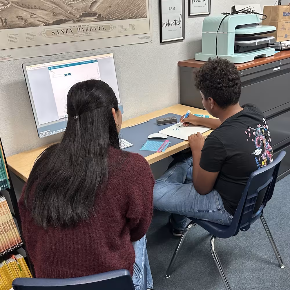 A student working with an instructor at a computer in a learning center.