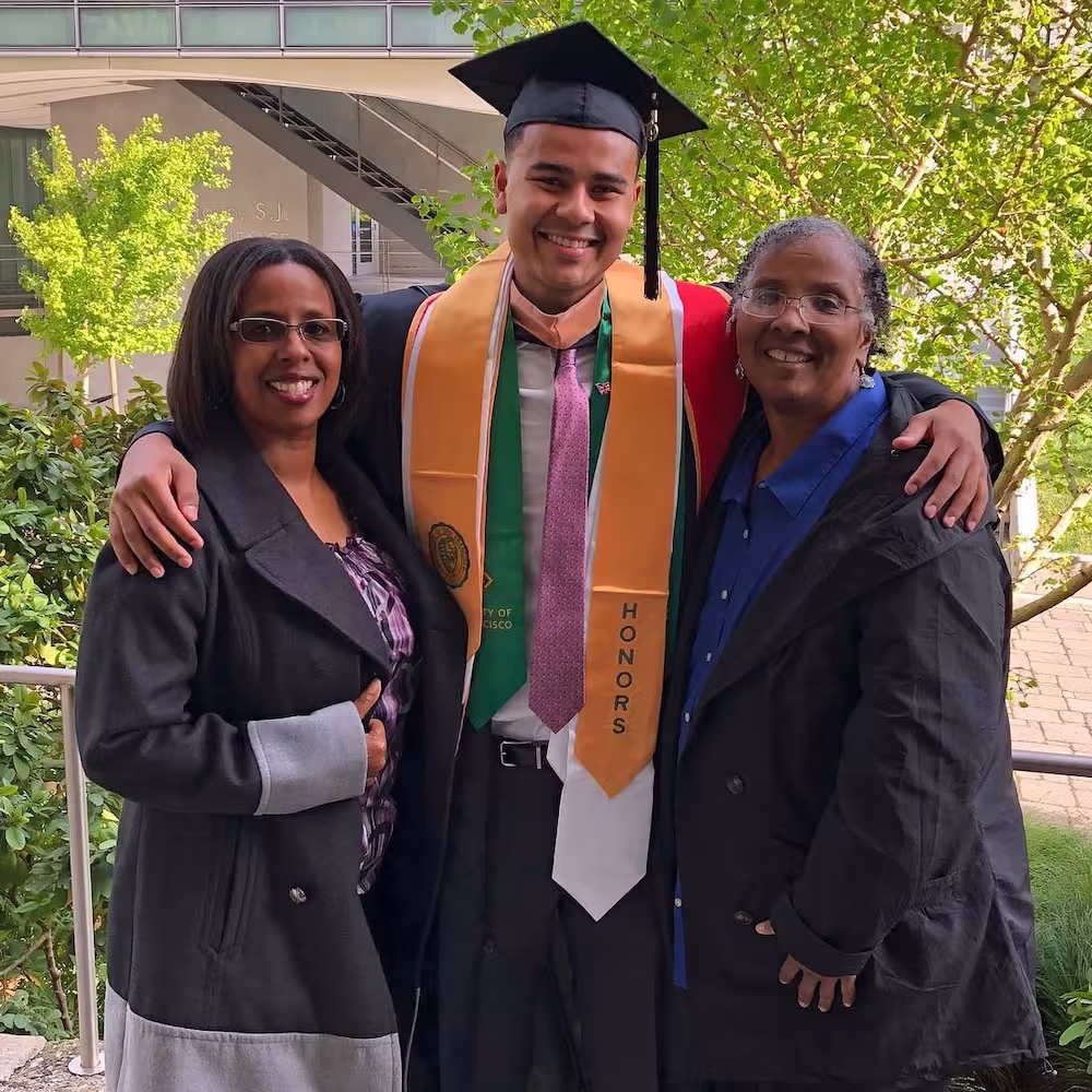 A graduate standing with Audrey and Connie after a graduation ceremony.